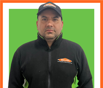 Denis, male SERVPRO employee in branded zip up hoodie with SERVPRO hat
